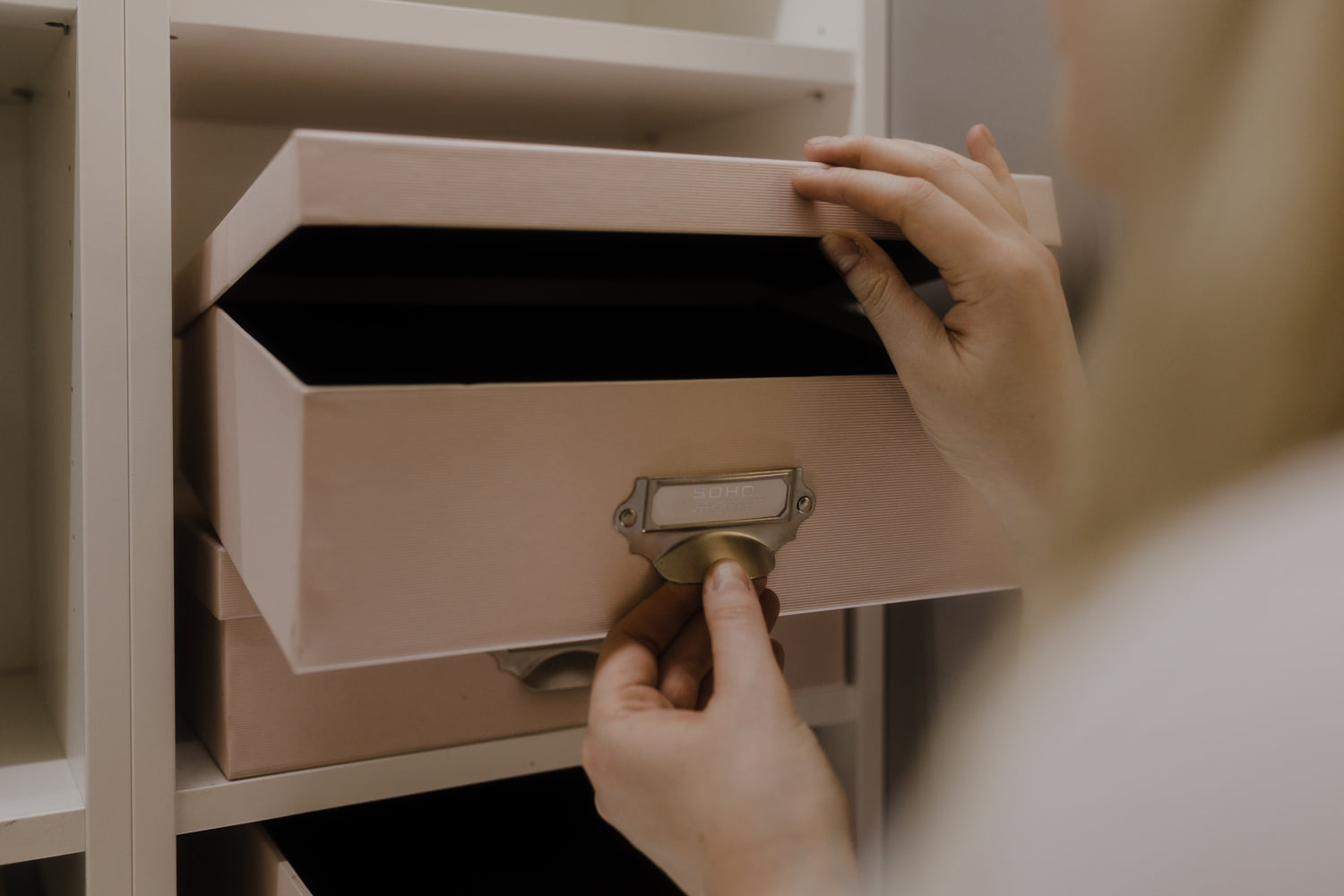 Aufbewahrungsbox mit Deckel in Rosa mit Metallgriff in einem Schrank.